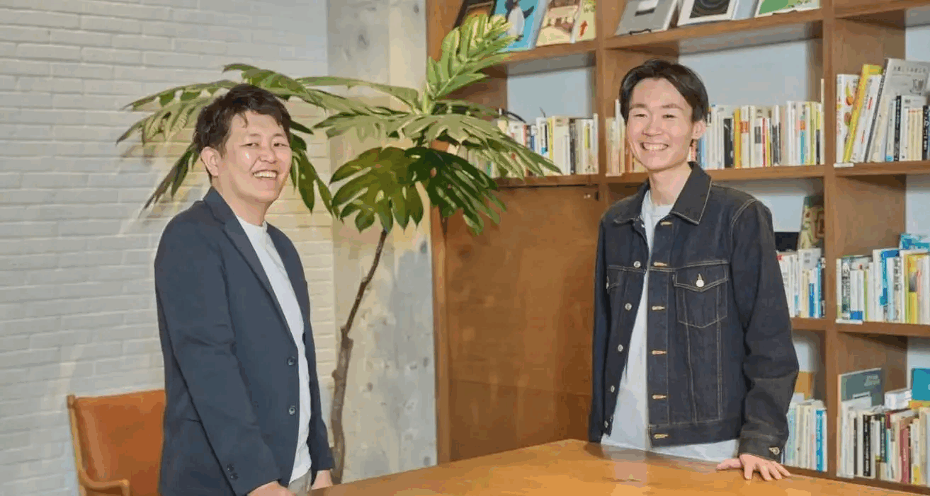 株式会社ブリューアス様の支援事例の写真。オフィスのラウンジで並んで立ち、笑顔を見せる藤田様とSells upの武田